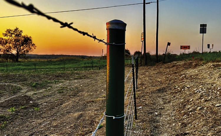 As the sun rises over Lampasas County, a new fence surrounds a vast hayfield, standing strong against the morning light. The sturdy metal posts and taut wire symbolize the resilience and determination of the agricultural community to rebuild JOYCESARAH MCCABE | DISPATCH RECORD